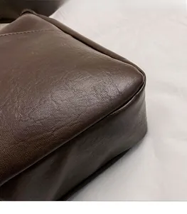 Close-up of fine stitching and soft leather texture on the bottom corner of dark brown bag
