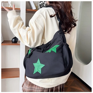 Dettaglio della borsa a secchiello nera con stella verde indossata da una modella