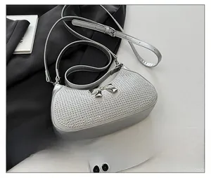 Macro detail of silver PU crossbody bag with sparkling rhinestones and metal bow accent