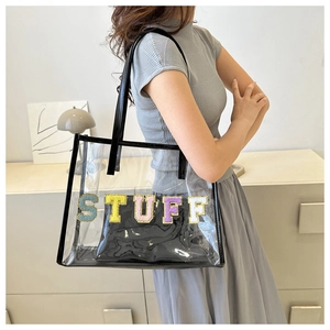 Detail of transparent PVC tote bag with colorful STUFF chenille patches on model