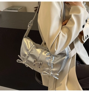 Close-up of metallic silver PU shoulder bag featuring decorative bow details and buckle