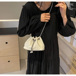 Detail of white satin drawstring bucket bag with silver chain strap and pearl charms