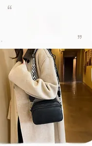 Détail du sac bandoulière noir grainé avec une large sangle tissée aux motifs de vagues