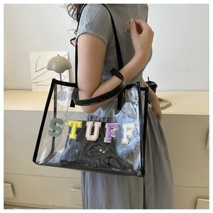 Detail of transparent PVC tote bag featuring black trim and colorful STUFF sequin embroidery