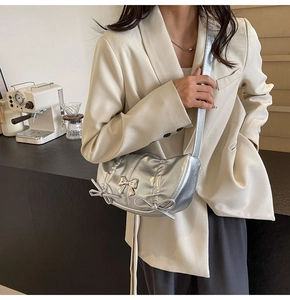 Detail view of silver metallic crossbody bag with triple bows and ruffled edges