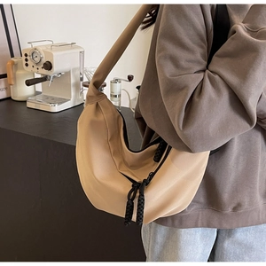 Detail of a khaki crescent nylon crossbody bag with black thick rope zipper and wide strap