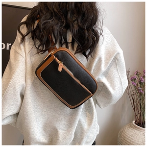 Detail of a two-tone crossbody bag with black leather texture and gold hardware zipper
