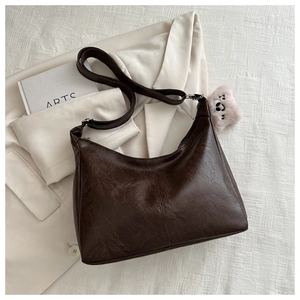 Brown faux leather hobo bag with vintage texture and cute plush bear charm on white fabric