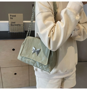 Sac en similicuir vert sauge avec boucle papillon argentée et bandoulière sur modèle