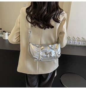 Silver crescent shoulder bag featuring stylish pleats and metallic bow details on the back