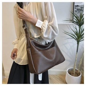 Detail of a large brown PU leather tote bag featuring fine texture and a front pocket