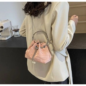 Detailed view of pink pleated bucket bag with metal ring handle and pearl drawstring