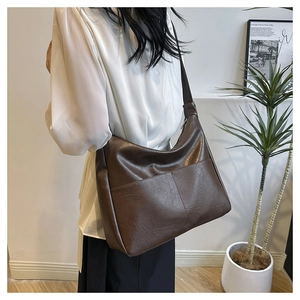 Detail view of large dark brown hobo bag with front pockets and retro leather texture