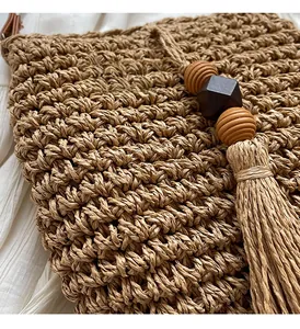 Nahaufnahme der gewebten Strohhandtasche mit Holzperlen und langen Quasten-Details