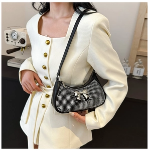 Detail of black crescent shoulder bag with silver rhinestones and metal bow accent