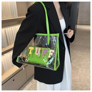 Detail of transparent PVC tote bag with neon green trim and colorful STUFF embroidery