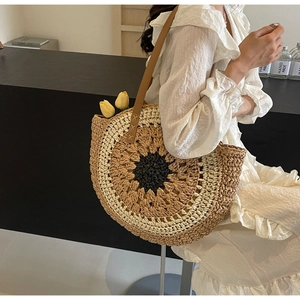 Detail of round straw beach bag with sunflower weave pattern and brown leather straps