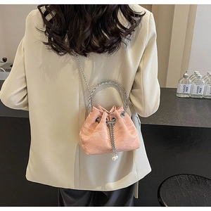 Detail of pink velvet bucket bag featuring silver ring handles and pearl drawstring accents