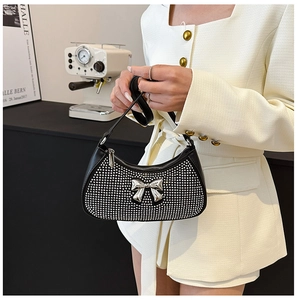 Detail of black PU leather shoulder bag with shiny rhinestones and a metal bow buckle