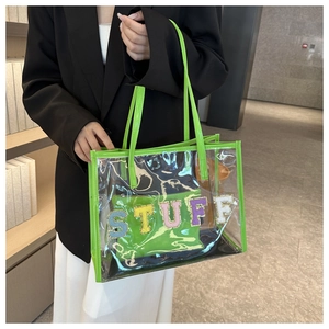 Macro detail of transparent PVC tote with green trim and STUFF towel embroidery insert