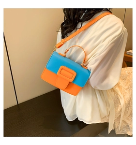 Detail of blue and orange contrast crossbody bag with large square buckle on model