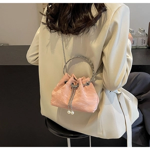 Detail of pink pleated bucket bag with silver metal ring handle and pearl drawstring