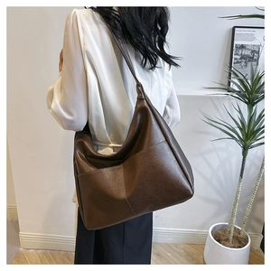 Side view of large dark brown PU leather hobo bag with wide shoulder strap on model