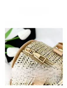 Détail de la fermeture éclair dorée sur le sac tressé beige avec bordure en cuir marron