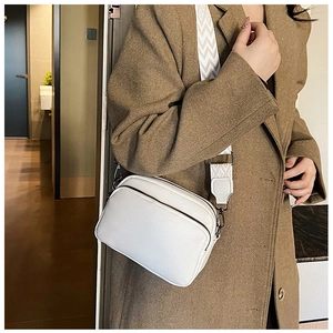 Sac bandoulière blanc à motif litchi avec large sangle ondulée porté par un mannequin