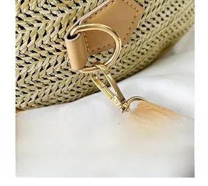 Gros plan des crochets dorés et du cuir marron clair sur un sac en paille tressé