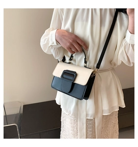 Detail of a chic cream and black contrast crossbody bag with a large buckle closure