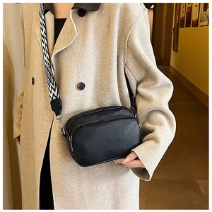 Détail du sac bandoulière en cuir grainé noir avec large sangle à motifs géométriques