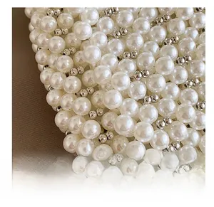 Detail of hand-woven white pearls and silver metal beads on a stylish handbag