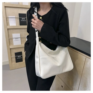 Minimalist white leather tote bag featuring practical front pocket and wide shoulder strap