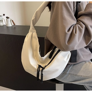 Detailed view of a white crescent shoulder bag with a unique black braided zipper puller