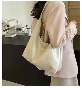 Detail of a minimalist cream PU leather hobo bag with a soft glossy finish on wide strap