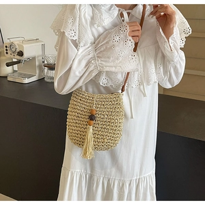 Detail der gewebten Strohschultertasche mit beiger Quaste und Holzperlenanhänger