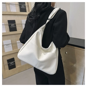 Detailed view of white textured leather Hobo shoulder bag worn by model in urban setting