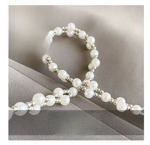 Detail of elegant pearl and silver bead woven shoulder strap on textured fabric