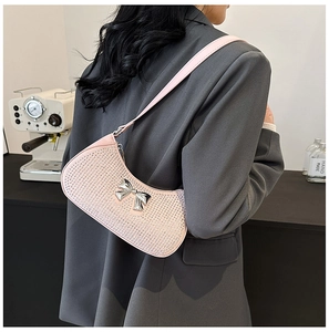 Pink rhinestone underarm bag with silver bow shown on shoulder with grey blazer