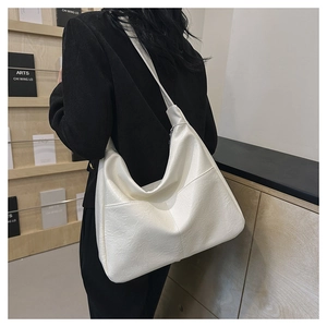 Detail view of white PU leather tote bag with soft pleated texture and wide strap