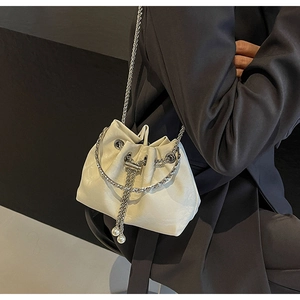 Detail of cream velvet drawstring bucket bag with silver chain and pearl charm