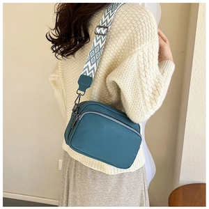 Vue détaillée du sac bandoulière en cuir bleu canard avec sangle tissée à losanges