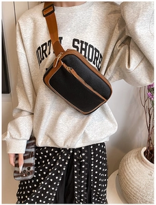 Close-up of black litchi grain PU leather crossbody bag with brown strap detail