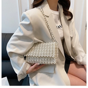 Detail of white faux pearl woven handbag with elegant long pearl crossbody strap