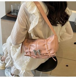 Detail of pink PU leather pleated shoulder bag with silver bow and knot accents