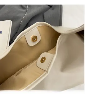 Detail view of golden magnetic clasps and inner zipper pocket of cream PU handbag