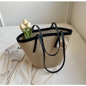 Chic beige woven straw tote bag with black leather handles and daisy floral accent