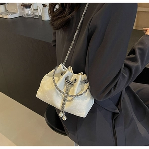 Detail of white velvet bucket bag featuring silver chain and large pearl ornaments