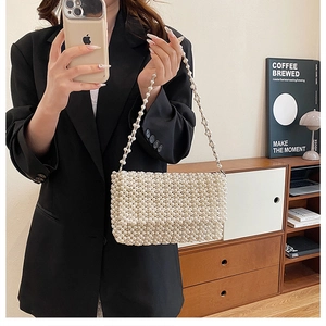 Detailed close-up of an elegant white handmade faux pearl beaded handbag with flap cover